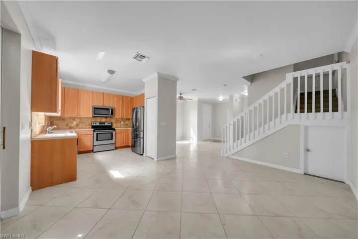 Kitchen with light countertops, ornamental molding, stainless steel appliances, a ceiling fan, and light tile patterned floors