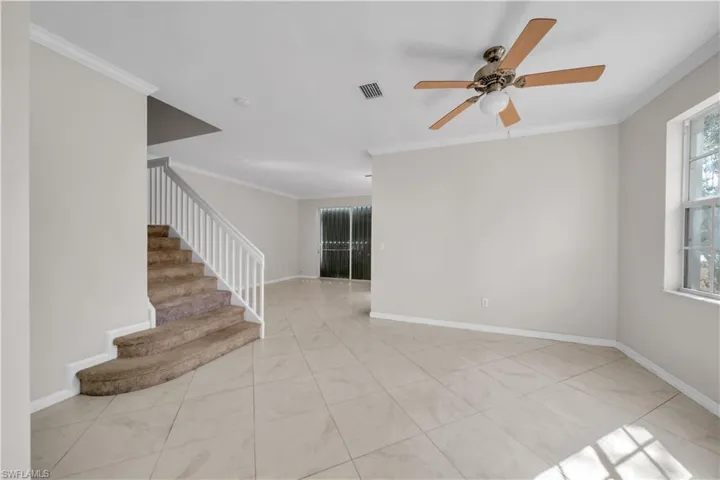 Spare room with crown molding, ceiling fan, and light tile patterned floors