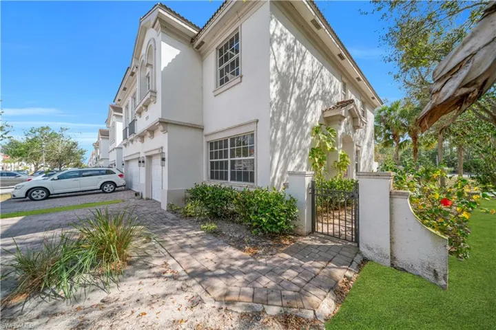 View of side of property with a gate, an attached garage, stucco siding, driveway, and a tile roof