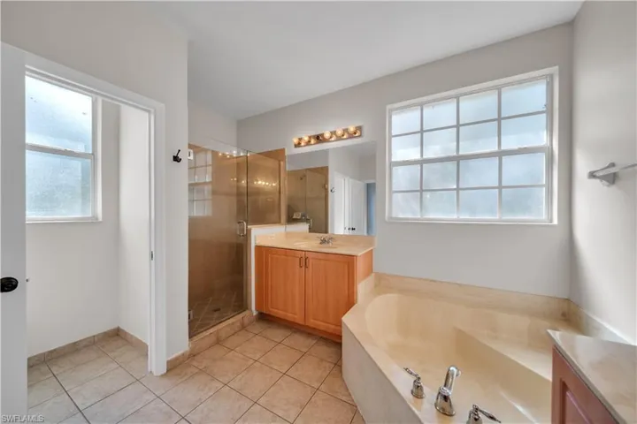 Bathroom featuring vanity, a shower stall, a garden tub, and light tile patterned flooring