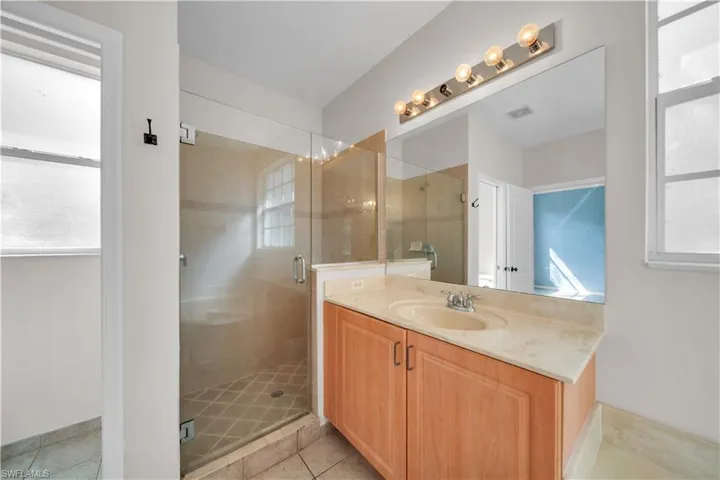 Bathroom with plenty of natural light, vanity, a stall shower, and light tile patterned floors