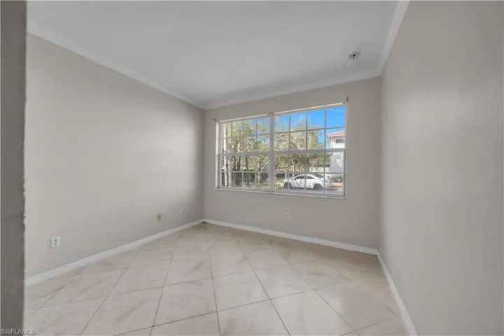 Empty room with ornamental molding and light tile patterned flooring