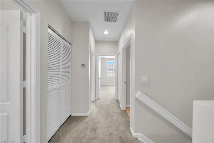 Hall with an upstairs landing, light carpet, and recessed lighting