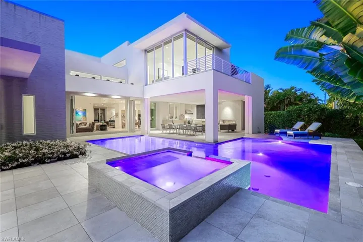 Dusk view of back of home, pool and spa