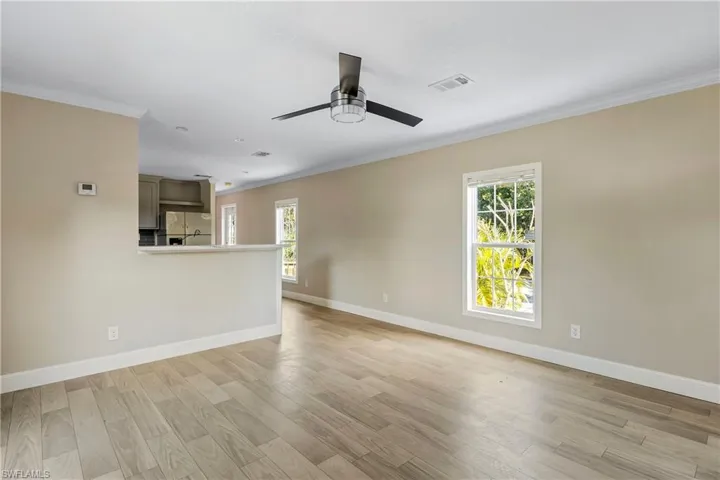 Unfurnished living room featuring ceiling fan, a healthy amount of sunlight, crown molding, and light hardwood / wood-style flooring