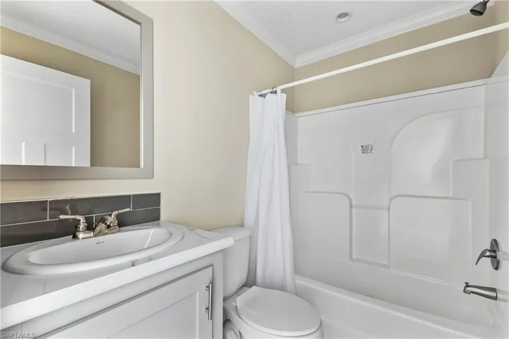 Guest Full bathroom featuring backsplash, toilet, ornamental molding, vanity, and shower / tub combo with curtain