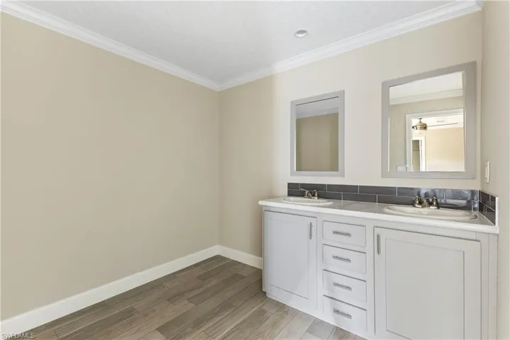 Main Bathroom with dual bowl vanity, ornamental molding, and hardwood / wood-style flooring