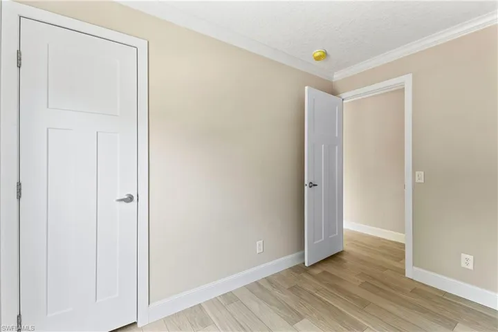bedroom 3 with a textured ceiling, ornamental molding, and light hardwood / wood-style flooring