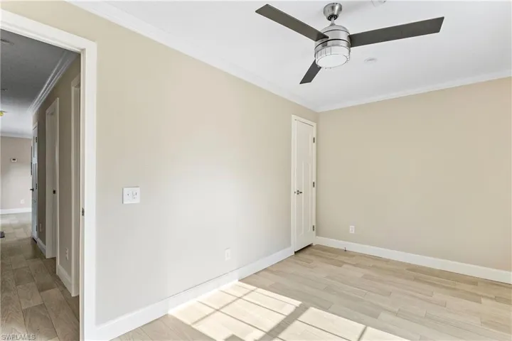 Bedroom 2 featuring light wood-type flooring, crown molding, and ceiling fan