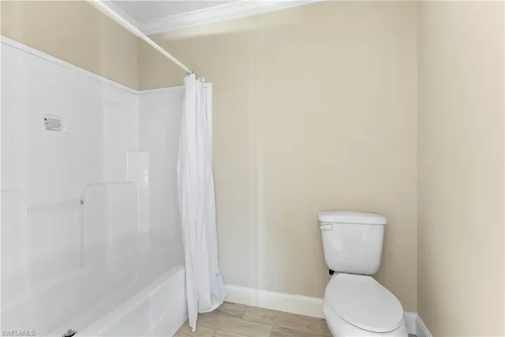 Main Bathroom with a textured ceiling, wood-type flooring, toilet, and shower / tub combo with curtain