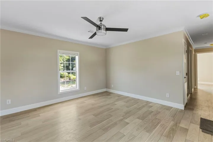 Spare room with ornamental molding, light wood-type flooring, and ceiling fan