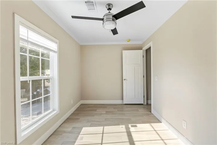 Bedroom with ceiling fan, light wood-type flooring, and crown molding