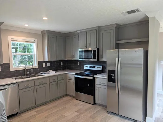 Kitchen featuring sink, tasteful backsplash, light wood-type flooring, and appliances with stainless steel finishes