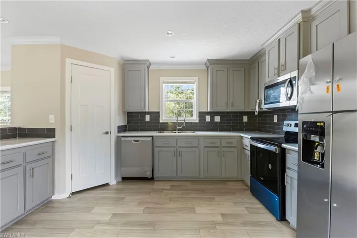 Kitchen with sink, backsplash, ornamental molding, and stainless steel appliances