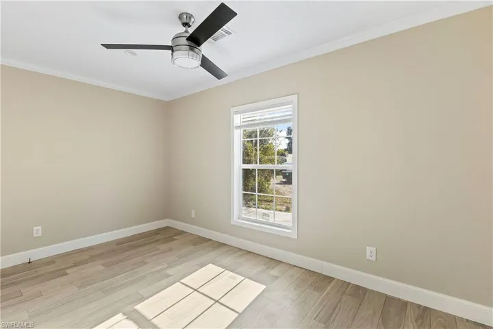 Empty room featuring ceiling fan, light hardwood / wood-style flooring, and ornamental molding