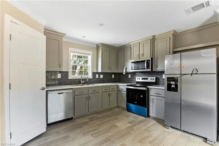 Kitchen featuring stainless steel appliances, sink, ornamental molding, and tasteful backsplash