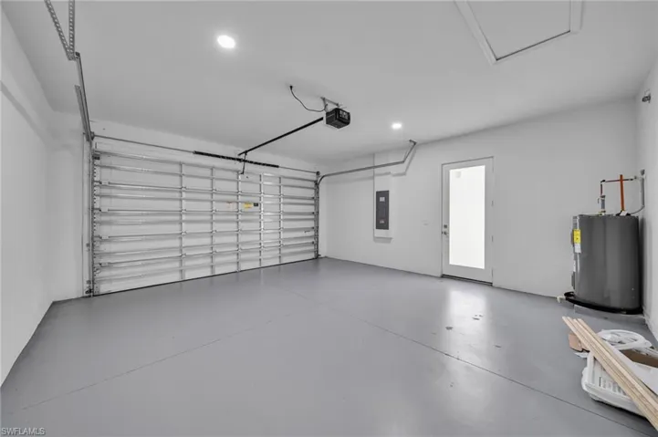 Garage featuring water heater, recessed lighting, electric panel, and a garage door opener