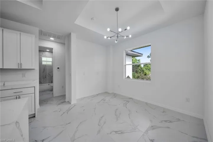 Unfurnished dining area with a chandelier and light marble finish floors
