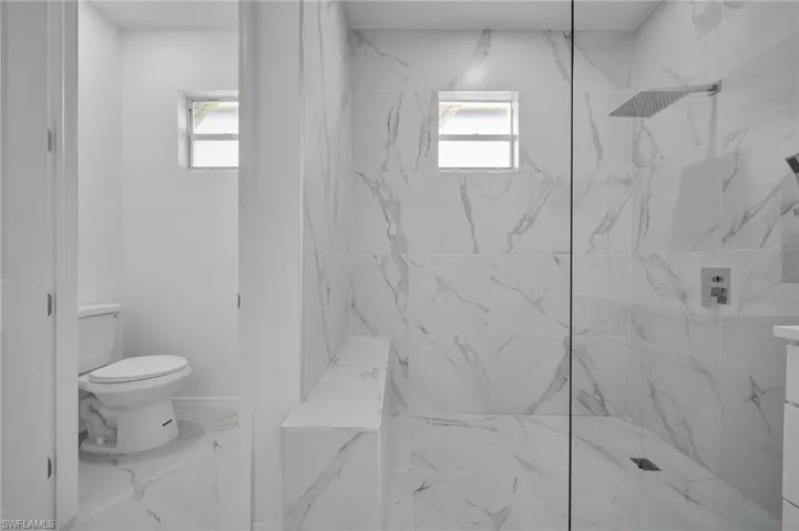 Bathroom with a marble finish shower and marble finish flooring