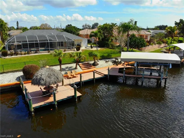 Dock area with boat lift, a water view, a sunroom, a lanai, and a pool
