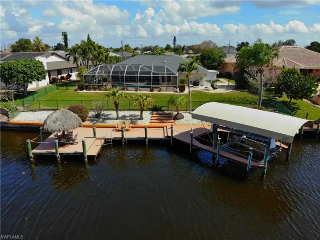 Dock with boat lift, a water view, a lanai, a sunroom, and an outdoor pool