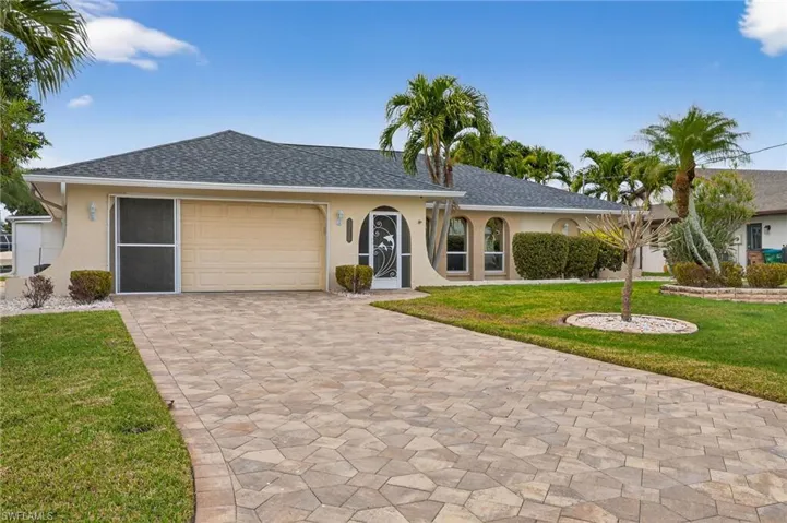 Ranch-style house with stucco siding, a front yard, decorative driveway, a garage, and roof with shingles