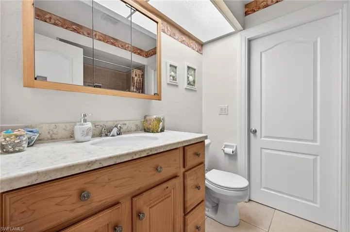 Bathroom with a textured wall, vanity, curtained shower, and light tile patterned floors