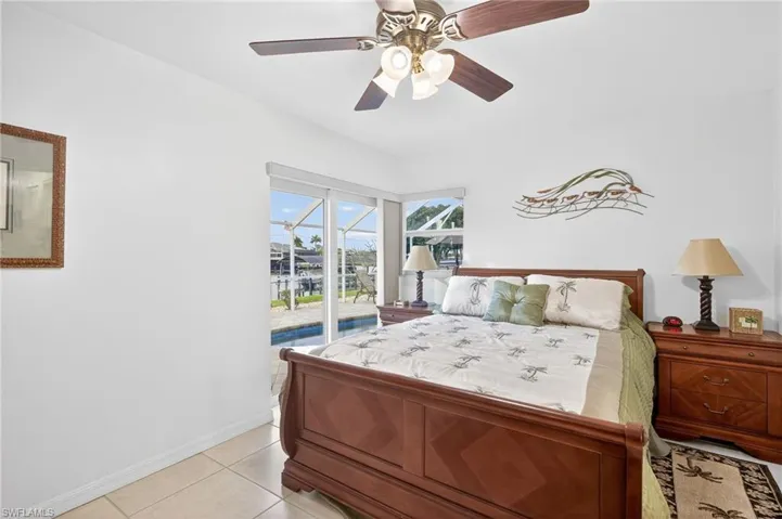 Bedroom with access to exterior, ceiling fan, light tile patterned flooring, and a sunroom