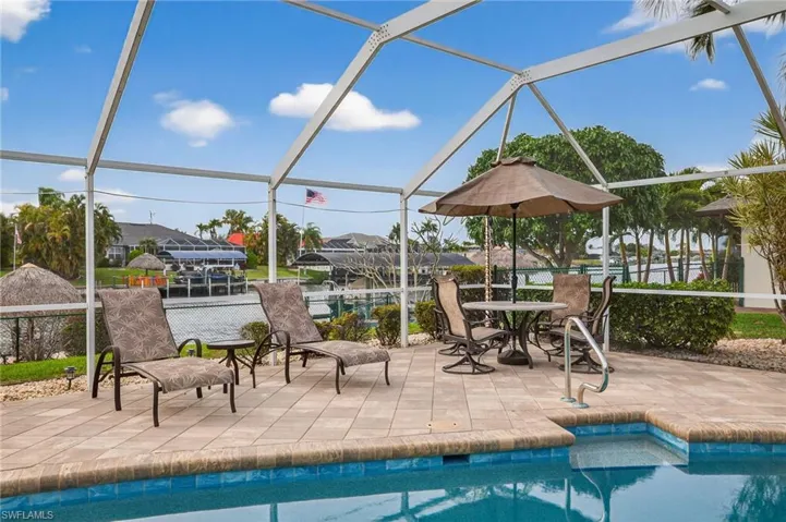 Swimming pool featuring a sunroom, glass enclosure, a patio, and outdoor dining area