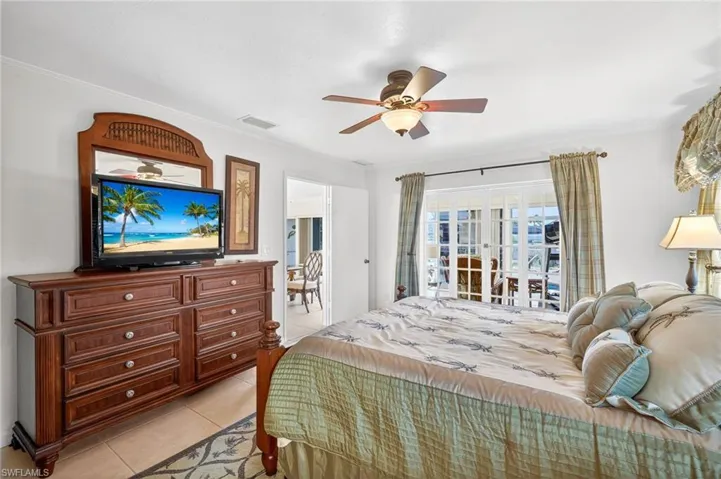 Bedroom with light tile patterned floors, ornamental molding, and a ceiling fan