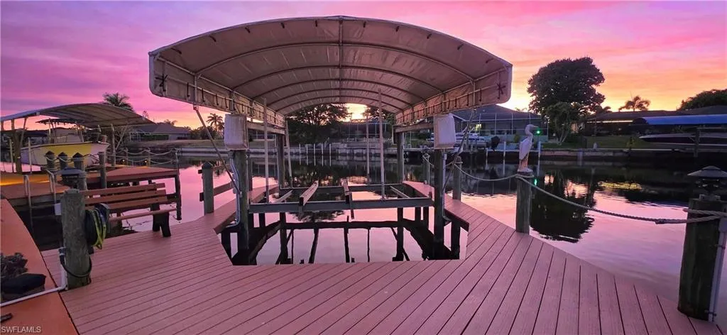 Deck at dusk with boat lift, a boat dock, and a water view