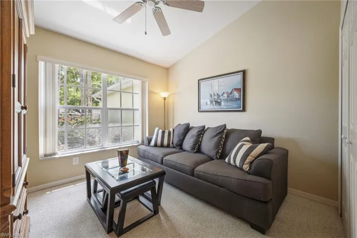 Living area featuring ceiling fan, baseboards, vaulted ceiling, and a healthy amount of sunlight
