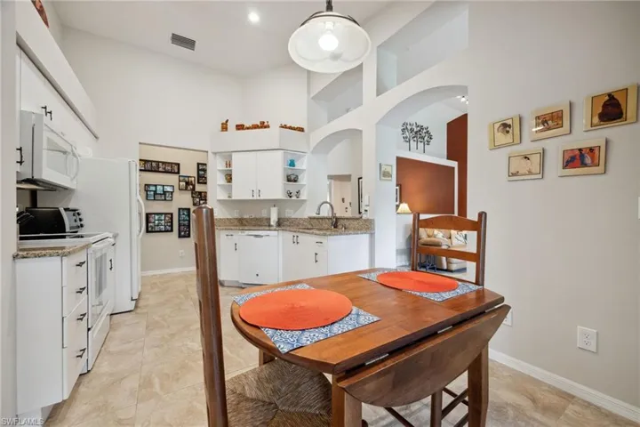 Dining space featuring baseboards, arched walkways, a towering ceiling, and visible vents