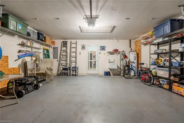 Garage featuring electric water heater and a garage door opener