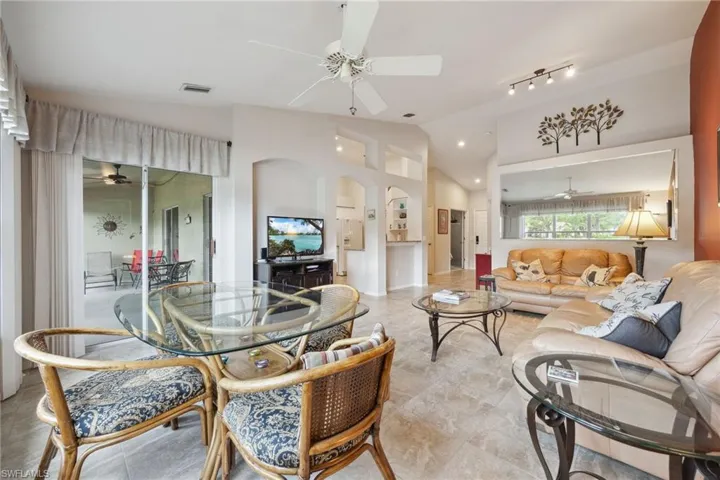 Living room with visible vents, a ceiling fan, arched walkways, and vaulted ceiling