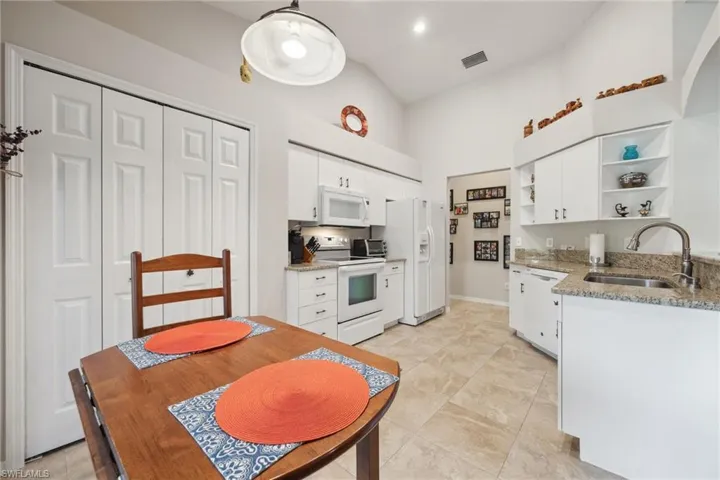 Kitchen featuring open shelves, a sink, white appliances, and white cabinets