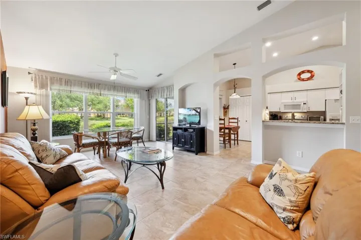 Living room featuring arched walkways, baseboards, a ceiling fan, and visible vents