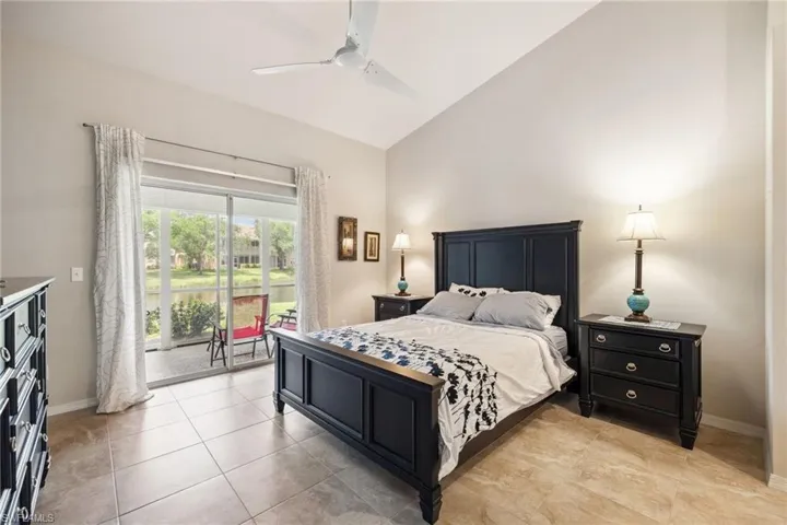 Bedroom with access to outside, baseboards, vaulted ceiling, light tile patterned flooring, and ceiling fan
