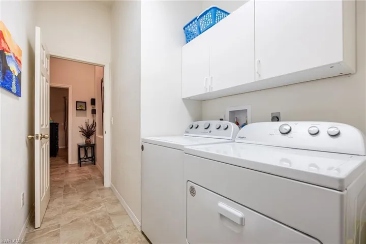 Laundry room featuring independent washer and dryer, baseboards, and cabinet space