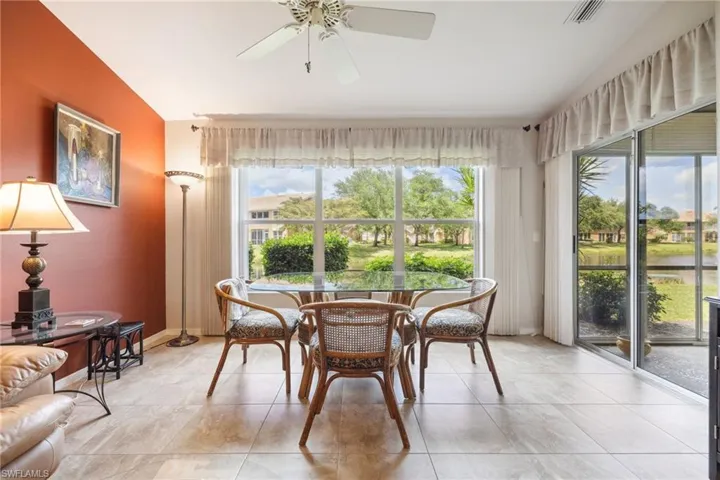 Dining area featuring light tile patterned floors, ceiling fan, visible vents, and lofted ceiling