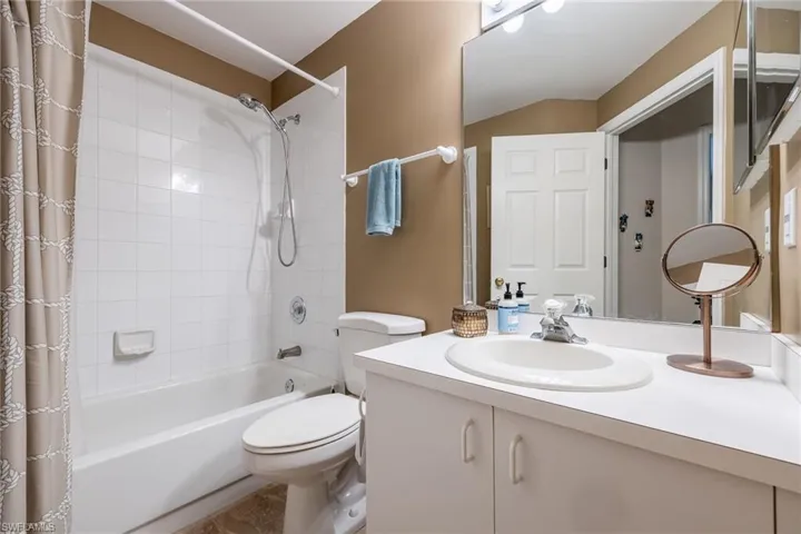 Full bath with toilet, shower / bath combo with shower curtain, and vanity