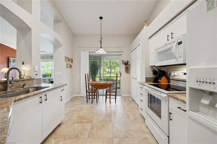 Kitchen featuring plenty of natural light, white appliances, white cabinetry, and a sink