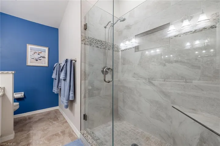Full bath featuring toilet, vanity, baseboards, and a stall shower