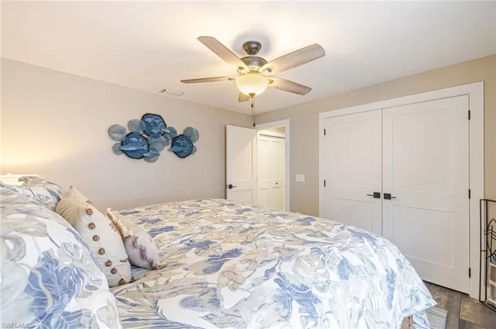 Recessed lighting and a ceiling fan fixture illuminate a room featuring two white panel doors with black hardware
