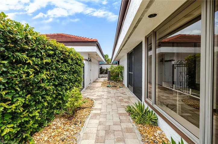 Paver walkway bordered by a manicured hedge and a decorative rock landscape bed