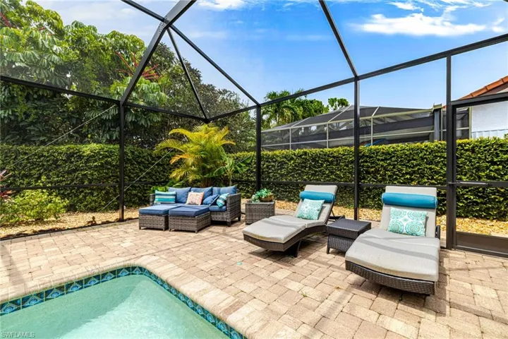 Screened outdoor living area featuring a paved patio and a swimming pool with decorative tile border