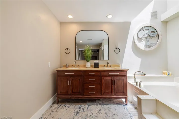 Double vanity with wood-finish cabinetry, light-toned countertop, and dual sinks