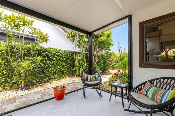 Screened patio featuring a textured concrete floor, a privacy hedge, and a paver pathway