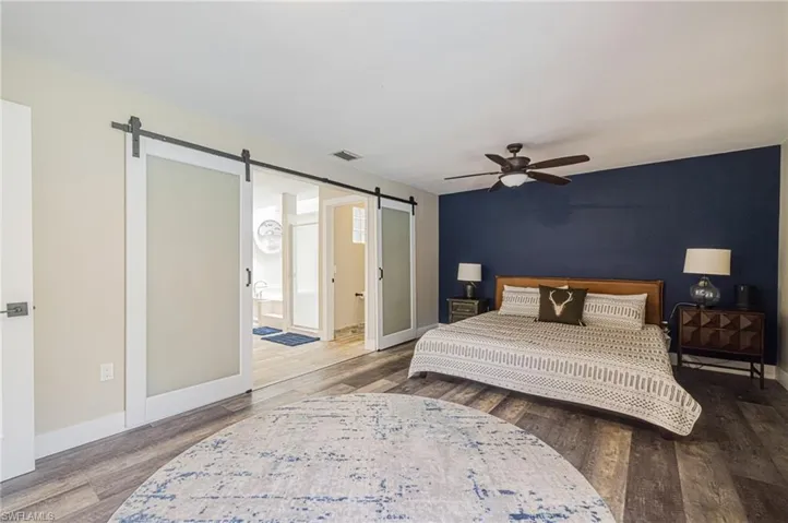 Spacious bedroom with wood-finish flooring and a ceiling fan