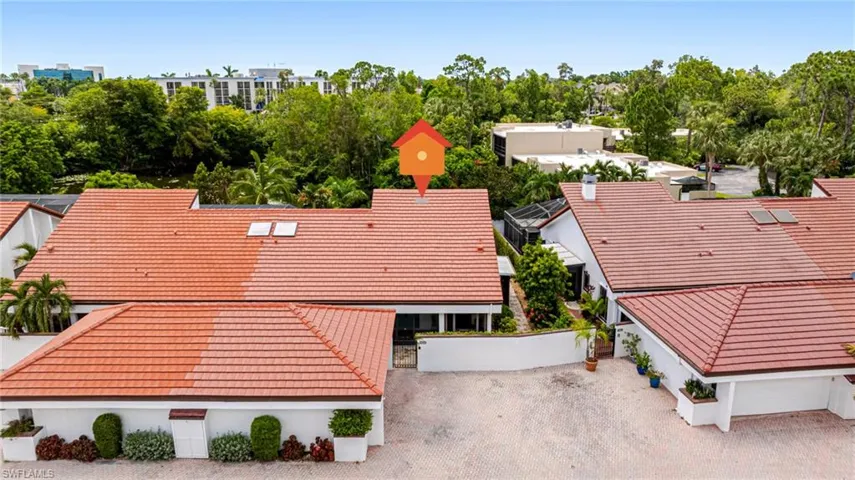 Red tile roof residences featuring white exterior walls and lush surrounding greenery